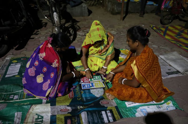 Women play a game of ludo as they wait to receive a token to receive a dose of COVISHIELD vaccine, outside a vaccination centre in Siliguri