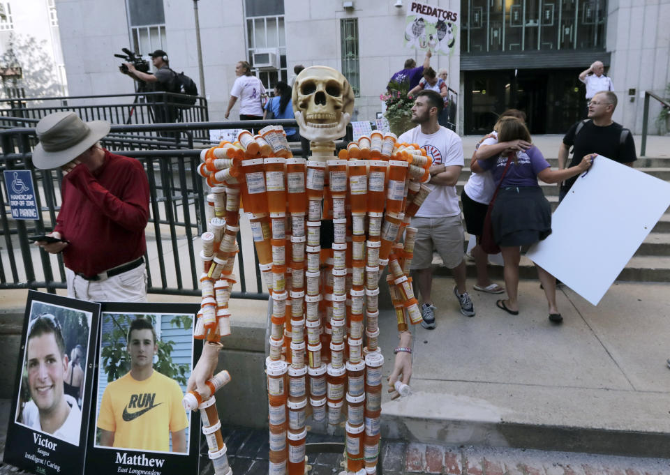 A skeleton of pill bottles stands with protesters outside a courthouse on Friday, Aug. 2, 2019, in Boston, where a judge was to hear arguments in Massachusetts' lawsuit against Purdue Pharma over its role in the national drug epidemic. The skeleton was created by Frank Huntley, of Worcester, Mass., from prescriptions he said he received while addicted to opioids. Organizers of the protest said they wanted to continue to put pressure on the Connecticut pharmaceutical company and the Sackler family that owns it. (AP Photo/Charles Krupa)