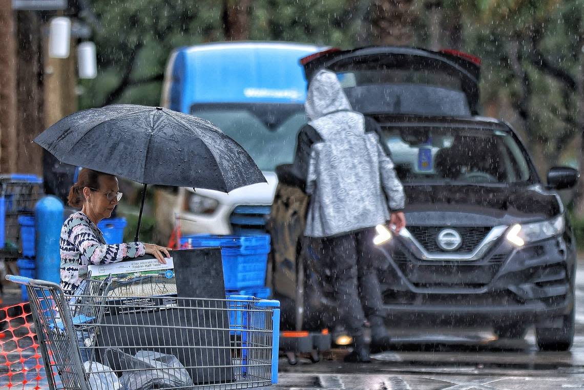 Despite the rainy weather condition, a shopper makes use of an umbrella as she heads to her car after shopping at Walmart in Pembroke Pines, Florida on Wednesday, December 13, 2023. Carl Juste/cjuste@miamiherald.com