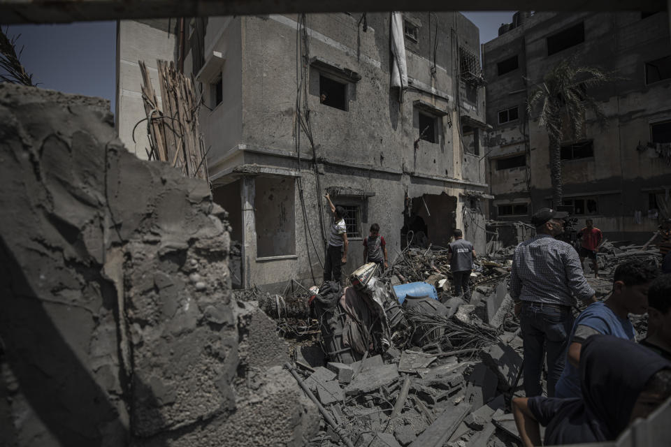 Palestinians inspect the rubble of destroyed residential building which was hit by Israeli airstrikes, in Gaza, Saturday, Aug. 6, 2022. Israeli jets pounded militant targets in Gaza as rockets rained on southern Israel, hours after a wave of Israeli airstrikes on the coastal enclave killed at least 11 people, including a senior militant and a 5-year-old girl. The fighting began with Israel's dramatic targeted killing of a senior commander of the Palestinian Islamic Jihad continued into the morning Saturday, drawing the sides closer to an all-out war. (AP Photo/Fatima Shbair)