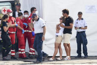 A man and a woman wait outside a tent where the body of one of the victims of a shipwreck was taken by rescuers, in Porticello, Sicily, southern Italy, Thursday, Aug. 22, 2024. Divers searching the wreck of the superyacht Bayesian that sank off Sicily on Monday recovered a fifth body on Thursday and continued to search for one more as investigators sought to learn why the vessel sank so quickly. The sign in Italian at right reads: 'Space reserved for the judicial authority and the medical examiner'. (AP Photo/Salvatore Cavalli)