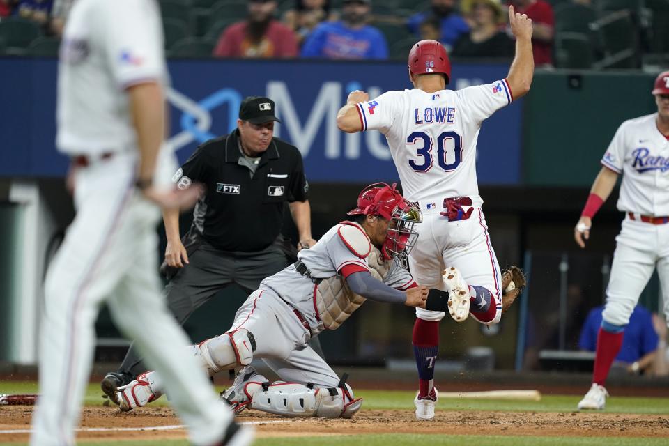 Los Angeles Angels catcher Kurt Suzuki, left, tags out Texas Rangers' Nathaniel Lowe (30) who was trying to score on a Jonah Heim single as umpire Doug Eddings looks on in the sixth inning of a baseball game in Arlington, Texas, Thursday, Sept. 22, 2022. (AP Photo/Tony Gutierrez)