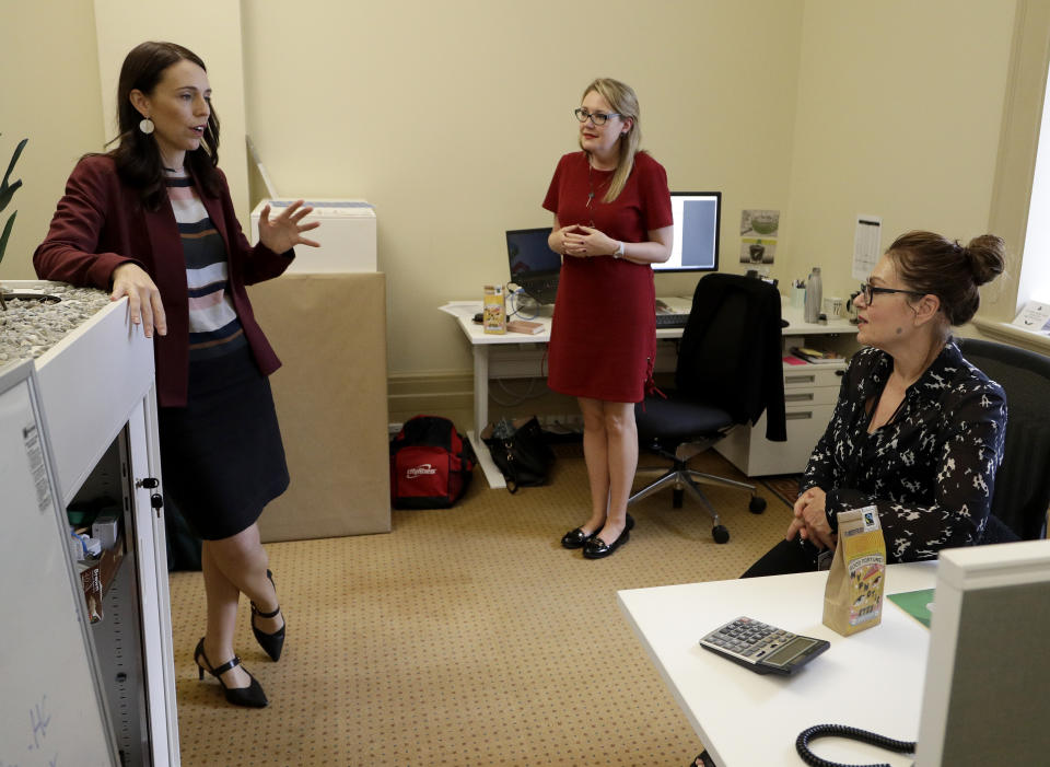 New Zealand Prime Minister Jacinda Arden, left, talks to reporters after handing out bags of coffee to the media as a Christmas present in Parliament in Wellington, New Zealand, Monday, Dec. 17, 2018. Prime Minister Ardern said that six months after giving birth, she's looking forward to spending more time with her daughter Neve over the Christmas break and thanking everybody who's helped her juggle responsibilities. She carried around a box to hand-deliver holiday treats of coffee and peanut brittle to reporters at Parliament. (AP Photo/Mark Baker)