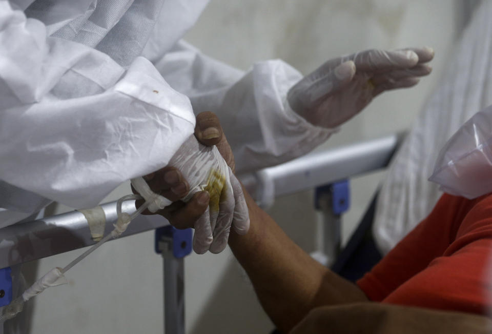 A nurse holds the hand of a patient in an effort to calm him as he gets breathless at the BKC jumbo field hospital, one of the largest COVID-19 facilities in Mumbai, India, Thursday, May 6, 2021. (AP Photo/Rafiq Maqbool)