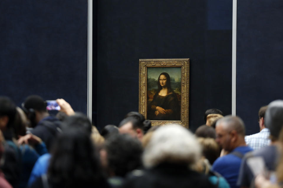 FILE - In this Oct.23, 2019 file photo, tourists wait to see Leonardo da Vinci's painting Mona Lisa, at the Louvre museum, in Paris. Iconic sites that are among some of France's biggest tourist draws won't reopen when the country lifts most of its coronavirus restrictions next week. Neither the Louvre Museum, the Eiffel Tower nor the Versailles Palace will be reopening next week when France lifts many of its remaining coronavirus lockdown restrictions. (AP Photo/Thibault Camus, File)