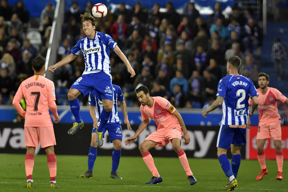 Deportivo Alaves Tomas Pina jumps for the ball against Barcelona forward Philippe Coutinho and midfielder Sergio Busquets during a Spanish La Liga soccer match between Deportivo Alaves and FC Barcelona at the Medizorrosa stadium in Vitoria, Spain, Tuesday, April 23, 2019. (AP Photo/Alvaro Barrientos)