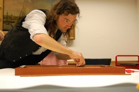 Conservation scientist Paul Garside carefully removes the 1970s wooden frame from the Burnt Magna Carta.