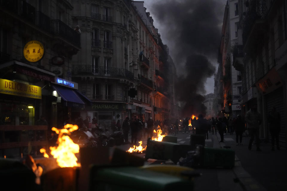 Protesters march behind by garbage cans as they demonstrate after French President Emmanuel Macron tried to diffuse tensions in a televised address to the nation, Monday, April 17, 2023 in Paris. Emmanuel Macron said Monday that he heard people's anger over raising the retirement age from 62 to 64, but insisted that it was needed. (AP Photo/Thibault Camus)