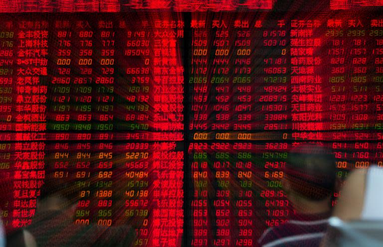 Investors look at stock prices at a securities exchange in Shanghai. The exchange rallied after a launch date for a trading link with Hong Kong was announced