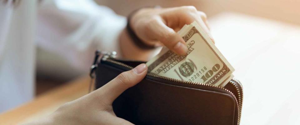 Hand holding 100 dollars bills in wallet.