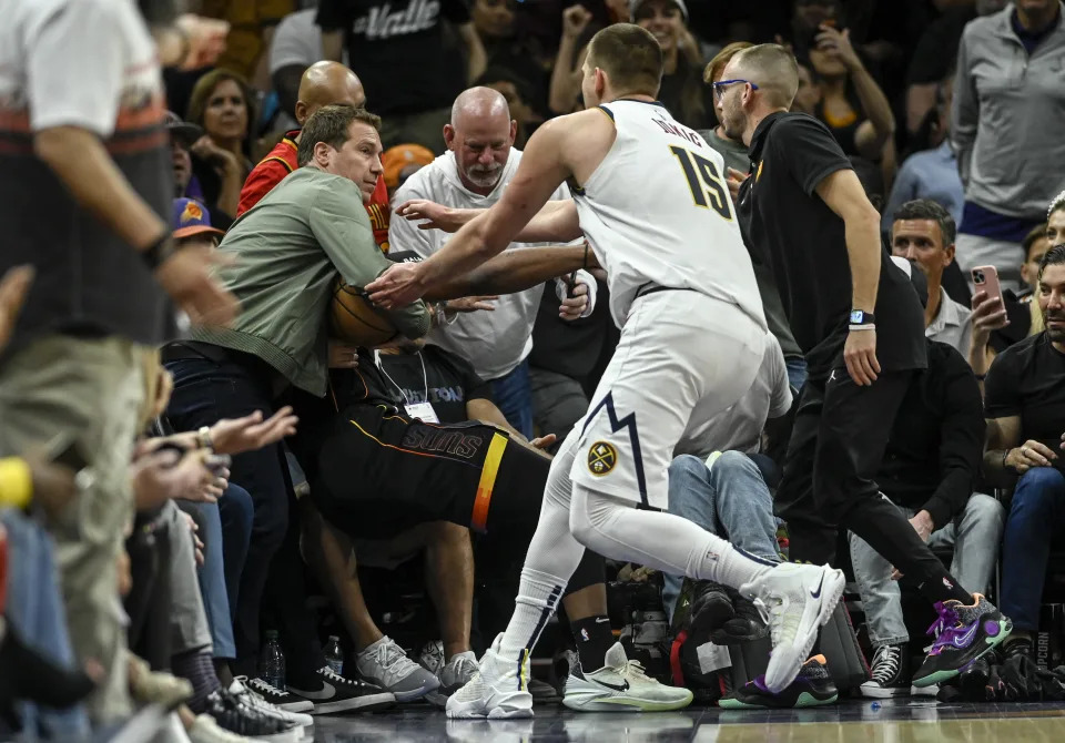 Nikola Jokić approaches Suns owner Mat Ishbia to take the ball from him. (AAron Ontiveroz/The Denver Post)