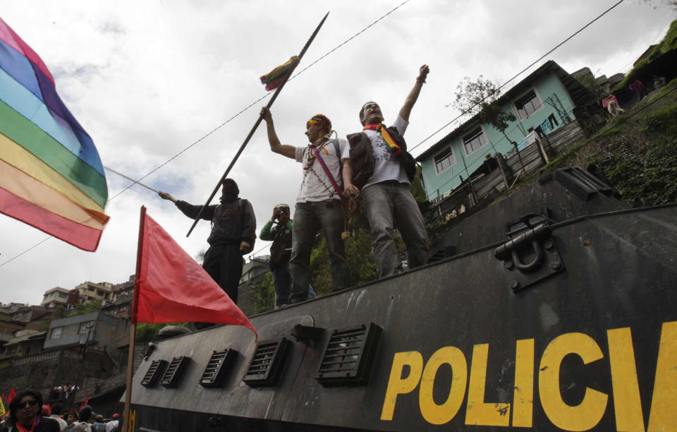 Protesters stand on a police vehicle during a march to protest President Rafael Correa's policies on mining in Quito, Ecuador, Thursday March 22, 2012. Protesters reached Ecuador's capital on Thursday after a two-week march from the Amazon to oppose plans for large-scaling mining projects on their lands. (AP Photo/Dolores Ochoa)