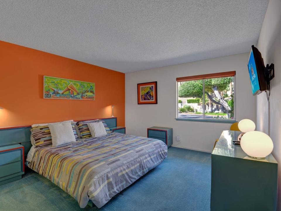 a guest bedroom at Disney's Palm Springs home with one wall painted orange and blue carpet