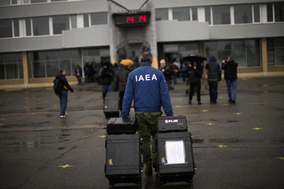 An International Atomic Energy Agency (IAEA) team member pulls suitcases with equipment as he arrives with others to Chernobyl nuclear power plant, in Chernobyl, Ukraine, Tuesday, April 26, 2022. (AP Photo/Francisco Seco)