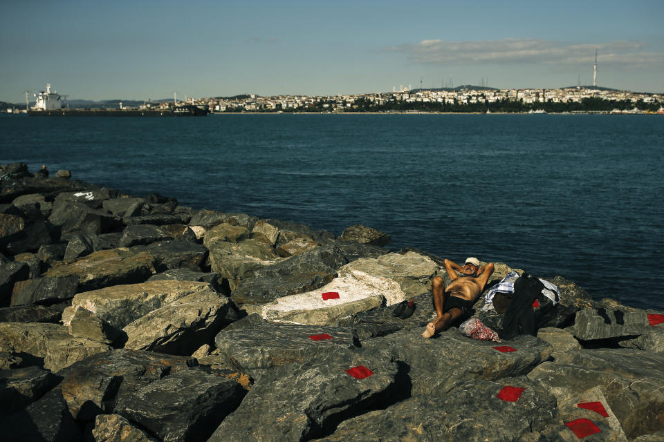 A man sunbathes during a four-day curfew declared by the government in an attempt to control the spread of coronavirus, outside Istanbul, Sunday, May 24, 2020. Turkey's senior citizens were allowed to leave their homes for a third time as the country continues to ease some coronavirus restrictions. (AP Photo/Emrah Gurel)