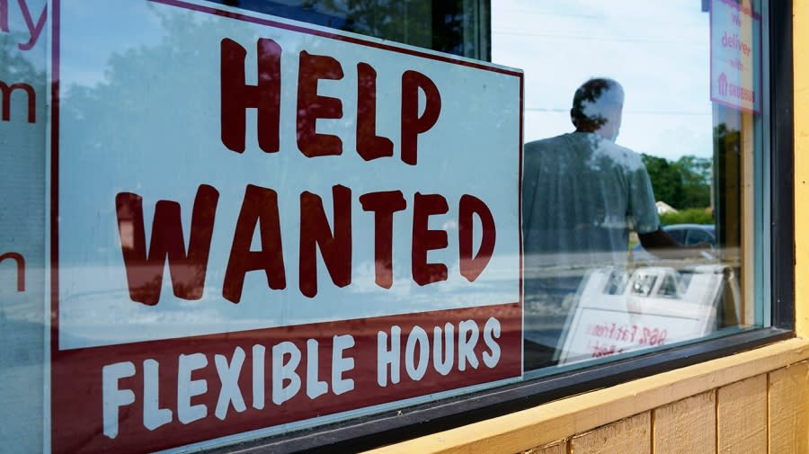 A help wanted sign sits in a window.