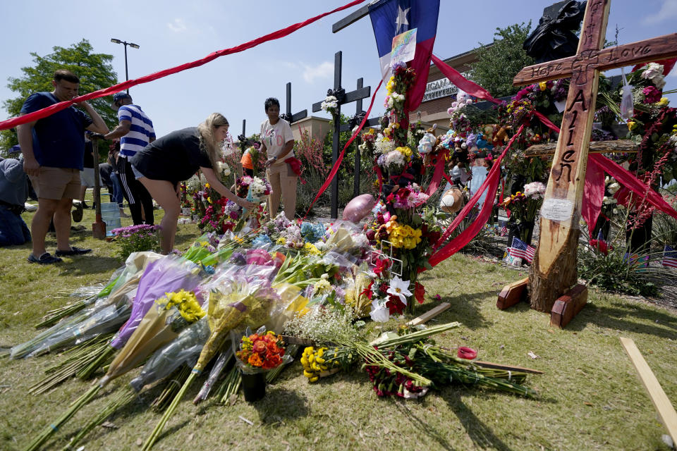 Visitors to a make shift memorial leave flowers in front of a large cross that has the words "Hope, Love, Allen", engraved into it at the mall where several people were killed, Monday, May 8, 2023, in Allen, Texas. (AP Photo/Tony Gutierrez)