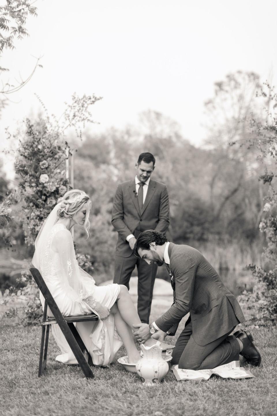 A groom washes his bride's feet during their wedding ceremony.