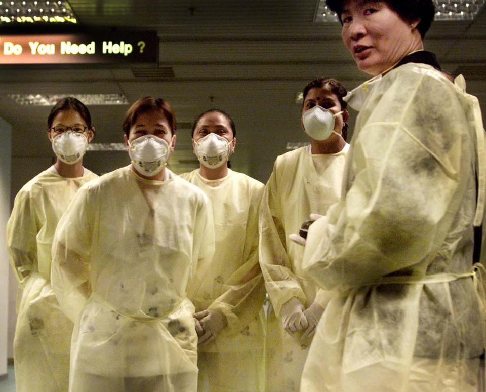 Nurses clad in yellow hospital gowns and surgical masks stand by at Changi International Airport in Singapore, Tuesday, April 1, 2003.