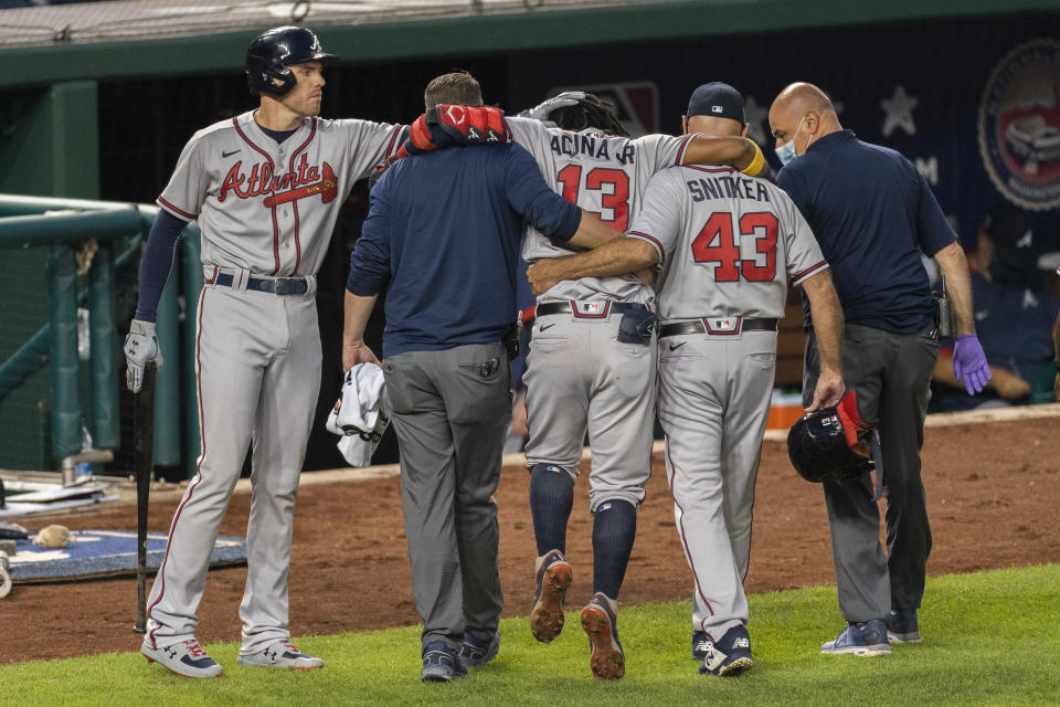 Atlanta Braves' Freddie Freeman, left, taps the head of Ronald Acuna Jr. (13) as Acuna is helped out of the field after fouling a ball off his left foot during the fourth inning of the team's baseball game against the Washington Nationals in Washington, Friday, Sept. 11, 2020. (AP Photo/Manuel Balce Ceneta)