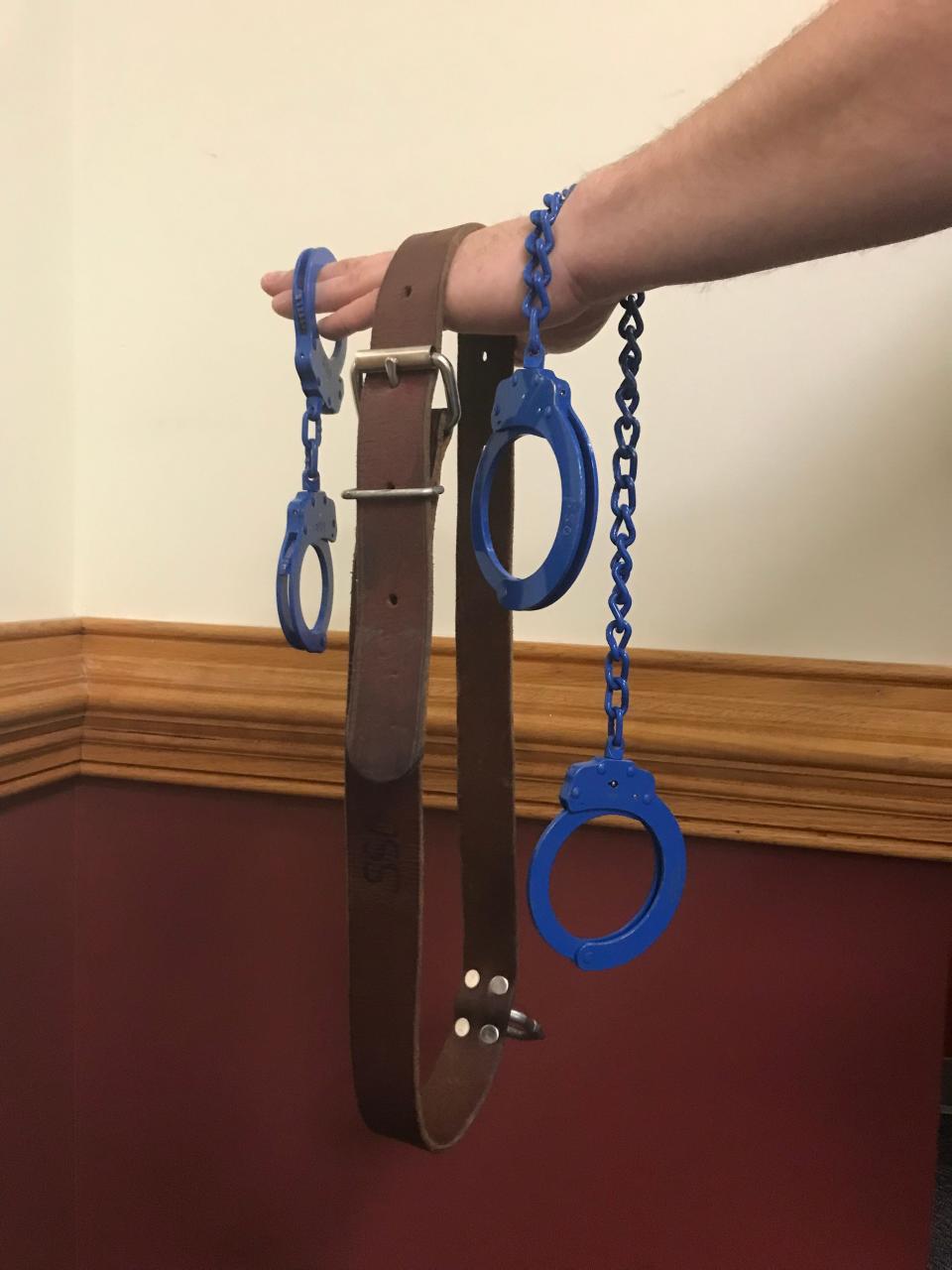 A Staunton Sheriff's deputy holds the wrist cuffs, leather belt and ankle cuffs that are put on all juvenile detainees making a court appearance in Staunton.