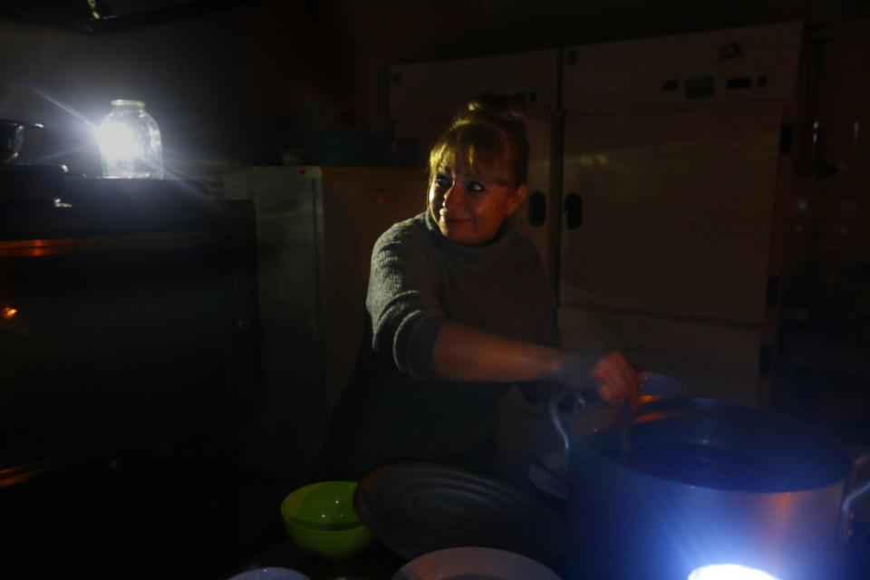 A woman cooks by candlelight.