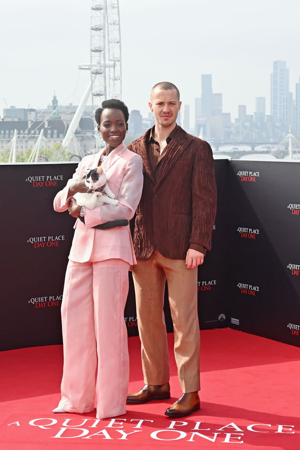 lupita nyong'o holding a cat, joseph quinn with a shaved head at the a quiet place day one photocall