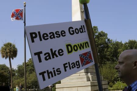 A demonstrator holds a sign at a rally outside the State House to get the Confederate flag (L) removed from the grounds in Columbia, South Carolina June 23, 2015. REUTERS/Brian Snyder