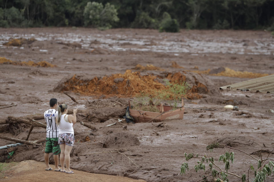 A couple with missing relatives look at the flooded area, after a dam collapsed in Brumadinho, Brazil, Saturday, Jan. 26, 2019. An estimated 300 people were still missing and authorities expected the death toll to rise during a search made more challenging by intermittent rains. (AP Photo/Andre Penner)