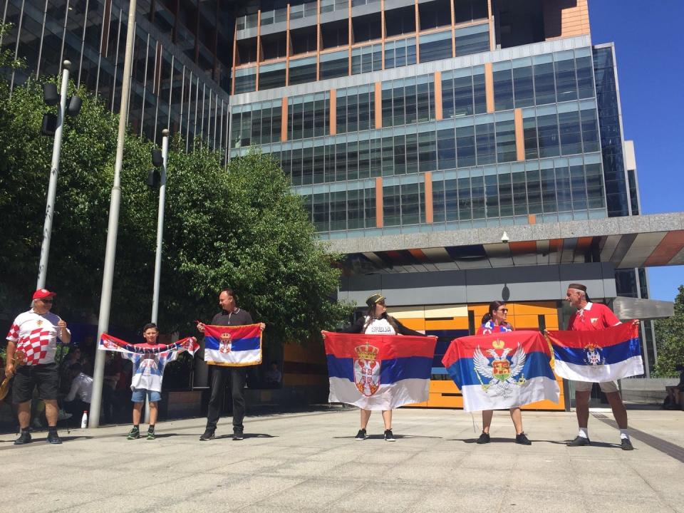 Supporters of Novak Djokovic hold Serbian flags.