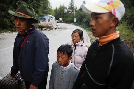 Locals stand on a mountain road that was hit by earthquake induced rockslides outside Jiuzhaigou, Sichuan province, China, August 10, 2017. REUTERS/Thomas Peter