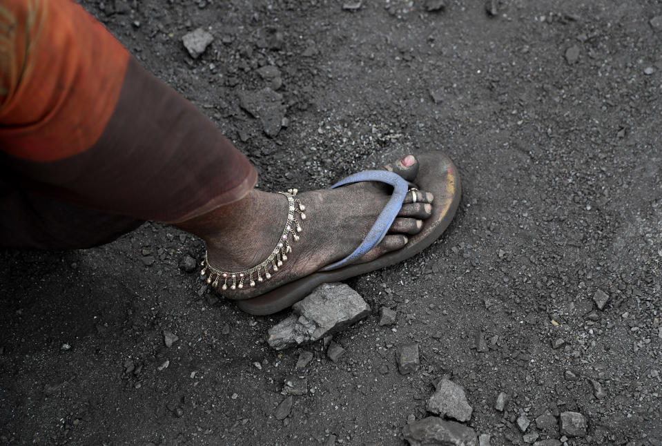 In this Oct. 23, 2019, photo, a laborer sports an anklet as she takes a break from loading coal into trucks for transportation in the village of Godhar in Jharia, a remote corner of eastern Jharkhand state, India. The fires started in coal pits in eastern India in 1916. More than a century later, they are still spewing flames and clouds of poisonous fumes into the air, forcing residents to brave sizzling temperatures, deadly sinkholes and toxic gases. (AP Photo/Aijaz Rahi)