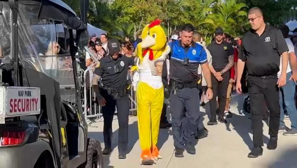 La policía de Miami aleja a un manifestante vestido con un traje de pollo de la inauguración el sábado del Dogs & Cats Walkway en el Museum Park de Miami.