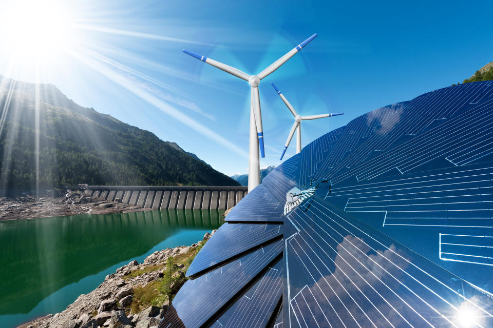 Solar panels and a wind farm next to a dam on a river