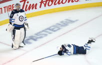 Winnipeg Jets' Josh Morrissey lays on the ice as Winnipeg Jets goaltender Connor Hellebuyck looks up at the replay following a short-handed goal by Montreal Canadiens' Joel Armia, not shown, during the second period of an NHL Stanley Cup playoff hockey game in Montreal, Sunday, June 6, 2021. (Paul Chiasson/The Canadian Press via AP)