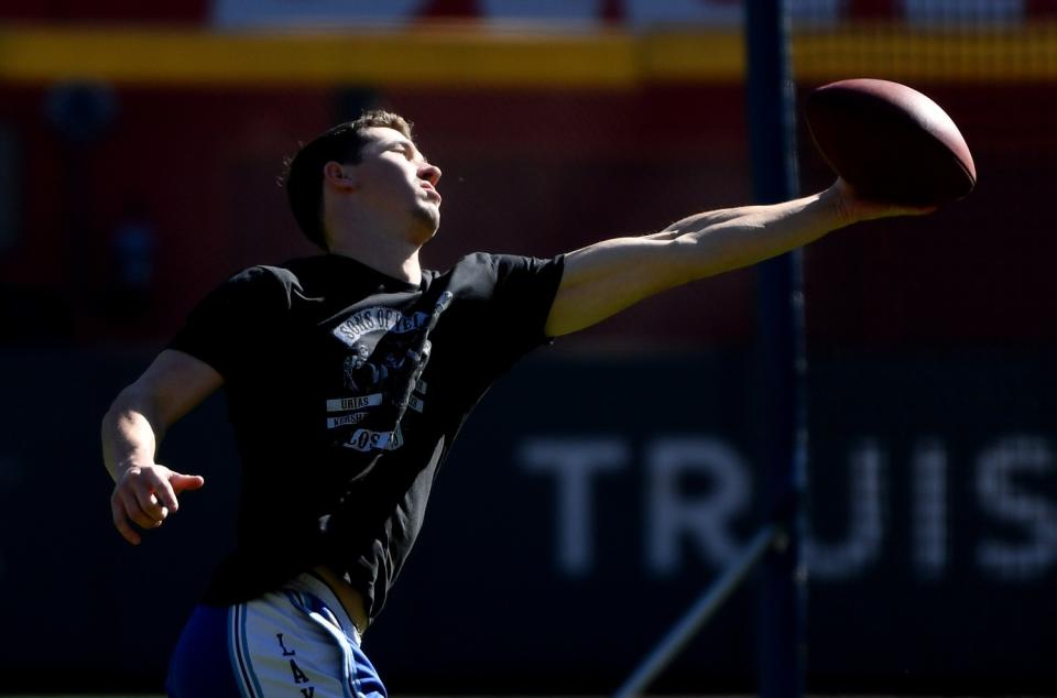 Los Angeles Dodgers pitcher Walker Buehler catches a football in the outfield before Game 1.