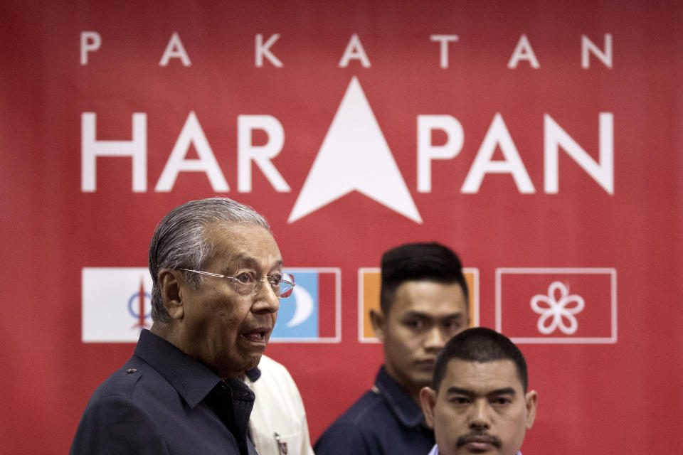 FILE - In this May 12, 2018, file photo, Malaysia's Prime Minister Mahathir Mohamad, left, reacts to the reporters as he arrives for a press conference to announce his cabinet members in Petaling Jaya, Malaysia. Malaysia's king accepted Mahathir's shocking resignation Monday, Feb. 24, 2020, that came in tandem with plans by his supporters to team up with opposition parties to form a new government and foil the transition of power to his named successor, Anwar Ibrahim. (AP Photo/Andy Wong, File)