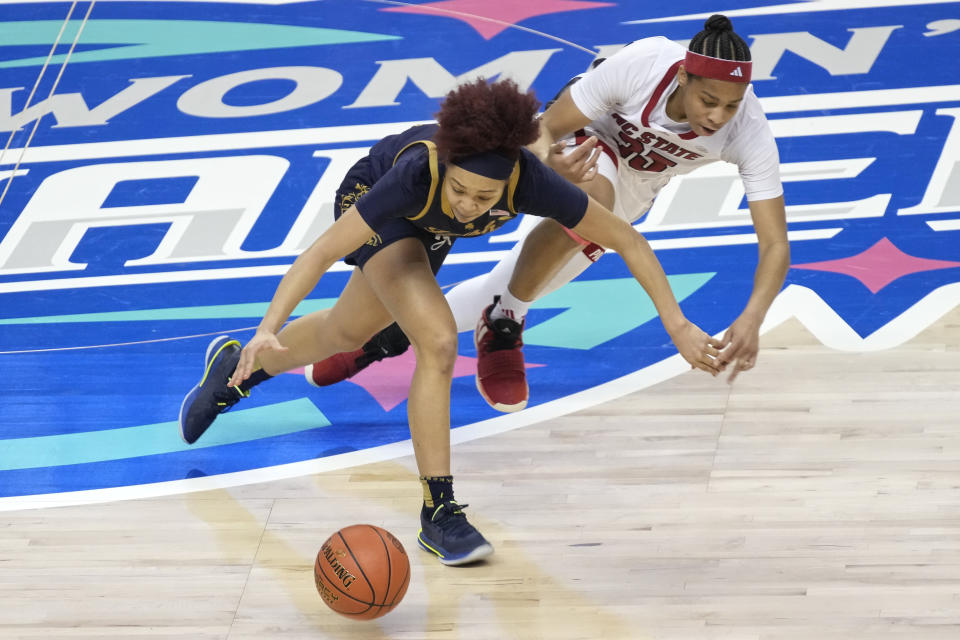 Notre Dame's Hannah Hidalgo, left and NC State's Zoe Brooks, right, chase a loose ball during the second half of an NCAA basketball game for the Women's Atlantic Coast Conference championship in Greensboro, N.C., Sunday, March 10, 2024. (AP Photo/Chuck Burton)