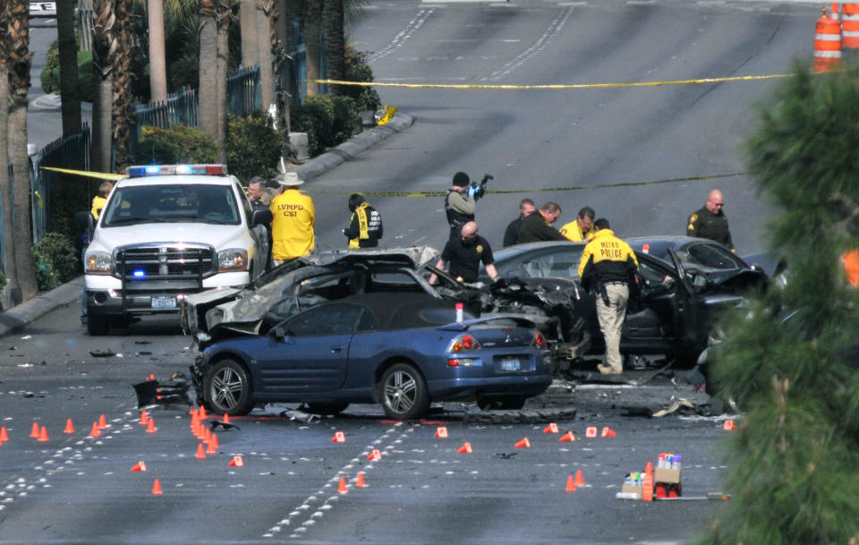 LAS VEGAS, NV - FEBRUARY 21: Las Vegas Metropolitan Police Department officers investigate the site of what is being described as a gun battle between shooters in vehicles along the Las Vegas Strip on February 21, 2013 in Las Vegas, Nevada. According to reports gunshots were fired between a black SUV and a Maserati, causing the Maserati to crash into a taxi that burst into flames. Five vehicles were involved in the subsequent crash with the Maserati driver and two people in the taxi being killed. (Photo by David Becker/Getty Images)