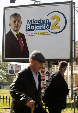 People walk under election billboards of the leading opposition candidate, Mladen Bojanic, in Tuzi, Montenegro, April 14, 2018. REUTERS/Stevo Vasiljevic