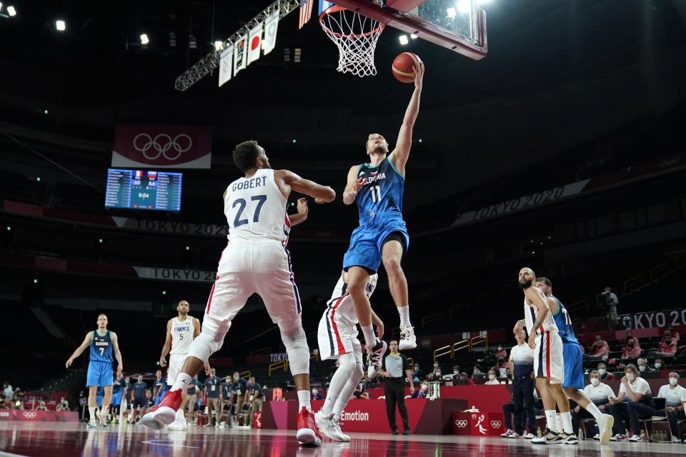 Slovenia's Jaka Blazic (11) drives to the basket over France's Rudy Gobert (27) during a men's basketball semifinal round game at the 2020 Summer Olympics, Thursday, Aug. 5, 2021, in Saitama, Japan. (AP Photo/Charlie Neibergall)