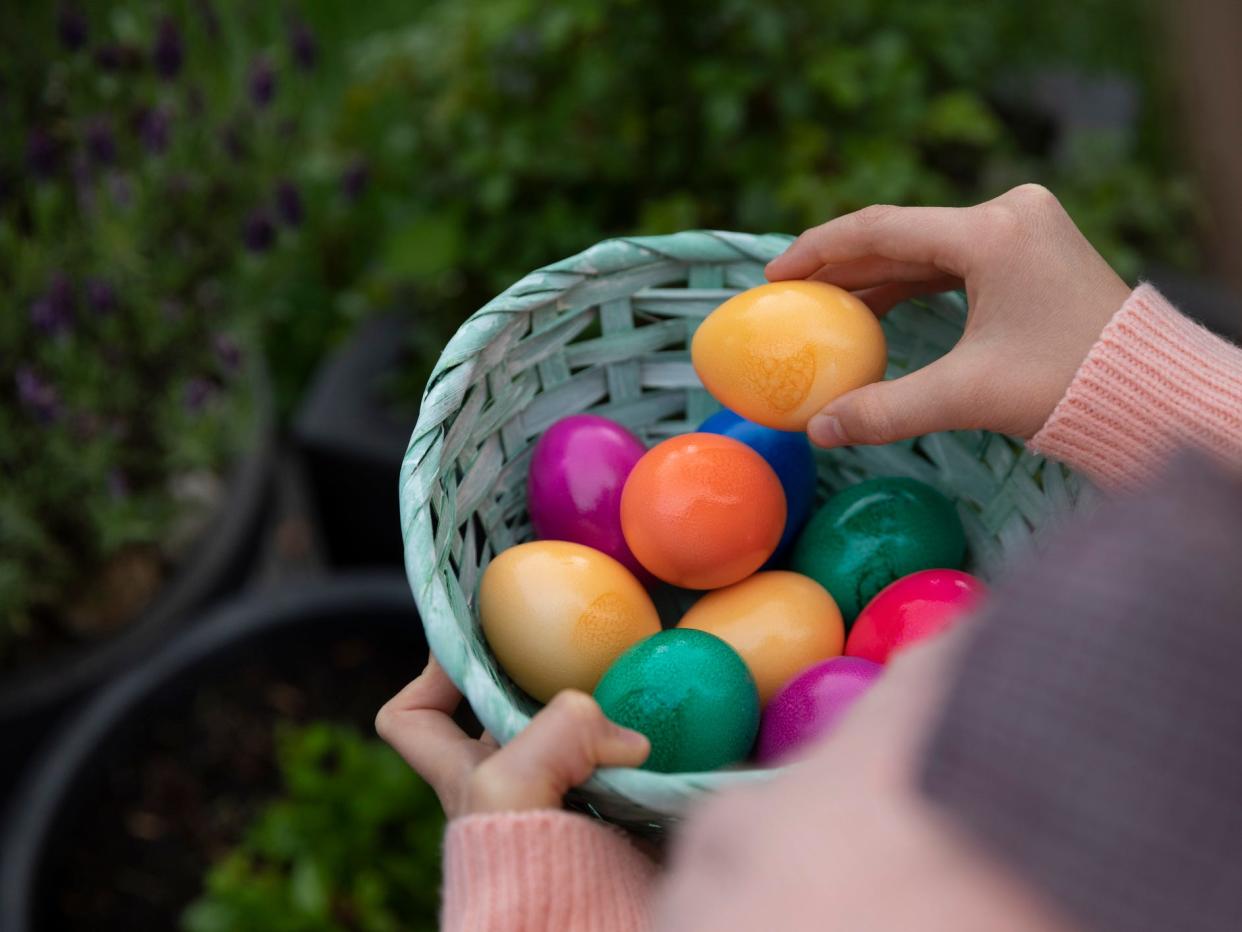 an Easter basket made of woven cardboard and filled with multicoloured dyed hens eggs in a back yard