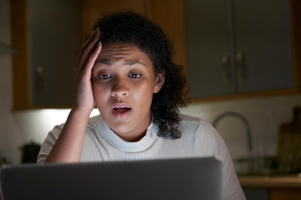 Unhappy Woman At Home With Computer Being Bullied Online On Social Media