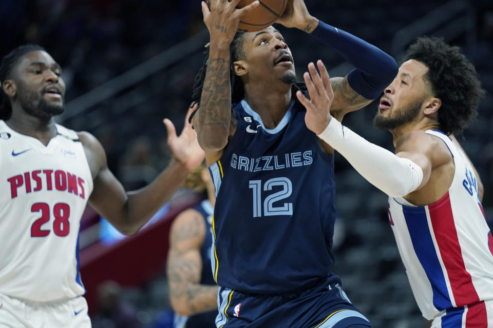 Memphis Grizzlies guard Ja Morant (12) attempts a layup as Detroit Pistons guard Cade Cunningham, right, defends during the second half of an NBA preseason basketball game, Thursday, Oct. 13, 2022, in Detroit. (AP Photo/Carlos Osorio)