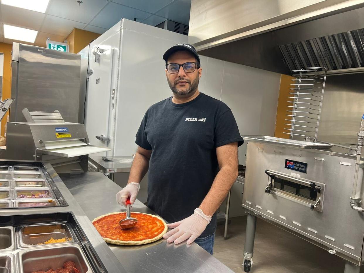 Rajwinder Singh making a pizza at his shop, Pizza Talks & Donair. The owner has been giving away 10 meals every week to those in need since November.  (Submitted by Rajwinder Singh - image credit)