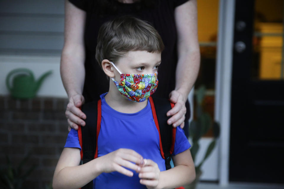 Rachel Adamus holds her son Paul, 7, on their porch before the bus arrives for the first day of school on Monday, Aug. 3, 2020, in Dallas, Ga. Adamus is among tens of thousands of students in Georgia and across the nation who were set to resume in-person school Monday for the first time since March. (AP Photo/Brynn Anderson)