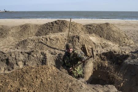 A Ukrainian serviceman digs trenches on a beach in the port city of Mariupol on the Azov Sea, March 20, 2015. REUTERS/Marko Djurica