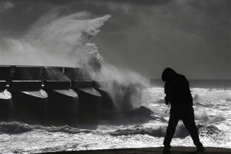 A man watches stormy seas in strong winds as waves crash on the harbour wall at Brighton marina in south east England October 28, 2013. REUTERS/Luke MacGregor