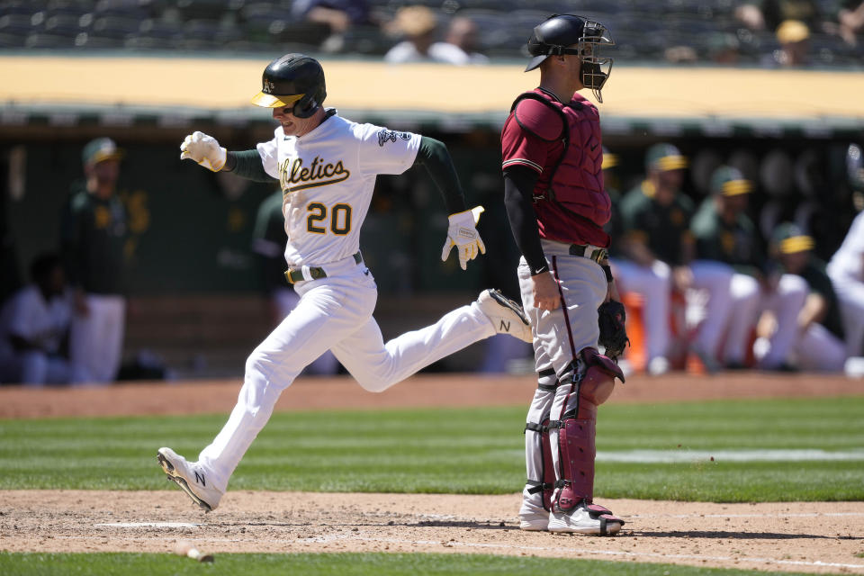 Oakland Athletics' Mark Canha, left, scores a run past Arizona Diamondbacks catcher Carson Kelly, right, on a sacrifice fly by Matt Olson during the seventh inning of a baseball game Wednesday, June 9, 2021, in Oakland, Calif. (AP Photo/Tony Avelar)