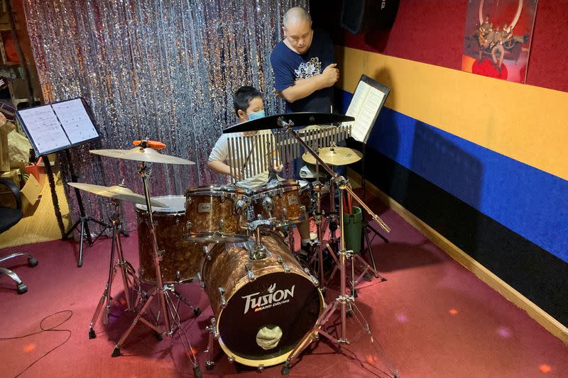 Dong Jun, drummer of a rock band "Zhong-D-Yin", conducts a drum lesson for a student at a studio in Shenzhen